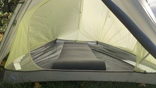 The interior of a Big Agnes Flycreek UL 2 tent, pitched on grass, showing the bathtub floor and a sleeping pad inside