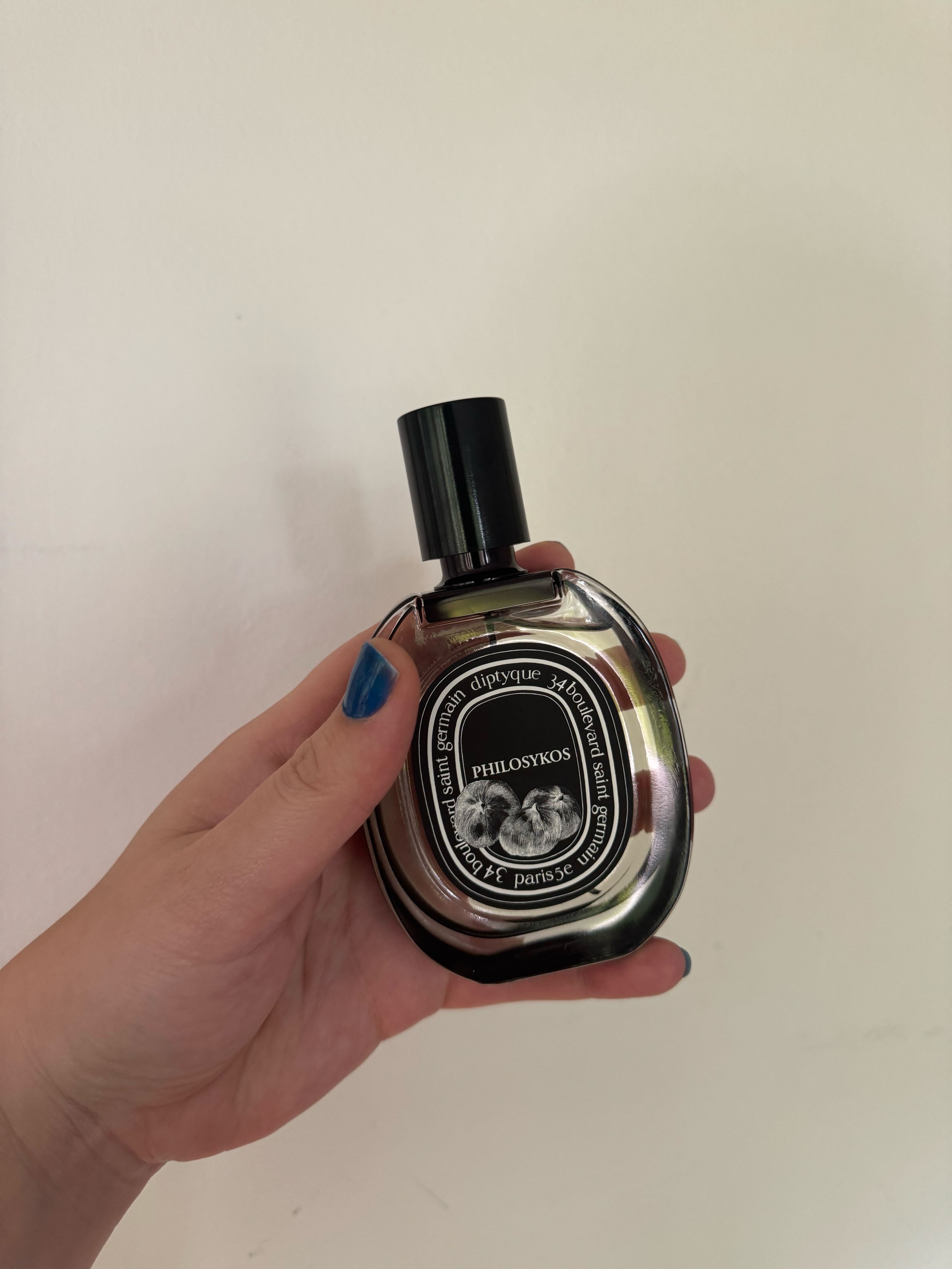 a woman&#039;s hand holding a glass Diptyque Philosykos Eau De Parfum