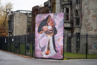 pink painting of clutched fist with burning fabric, canvas in public space
