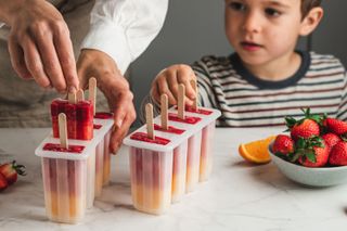 Close up of child and parent making homemade ice lollies