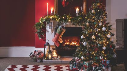 A Christmas tree in a home decorated Christmas tree decorating ideas, by a traditional fireplace in candlelight.