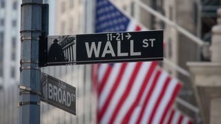A photo of a Wall Street sign in front of an American flag