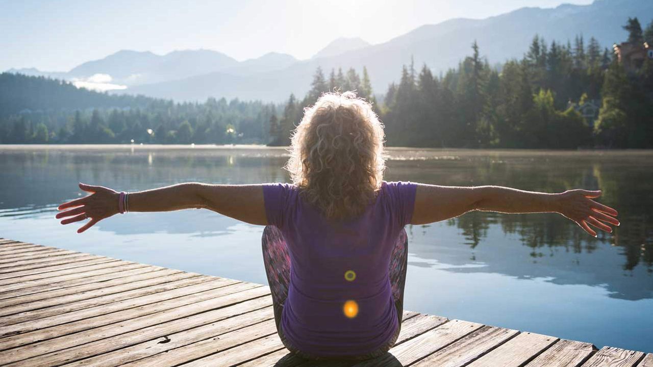 Woman does yoga on a lakeside dock