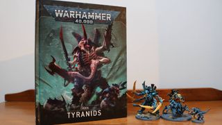 The Tyranid Codex on a wooden table, beside some miniatures
