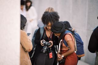 Two ladies holding canon camera dslrs and looking at the same screen