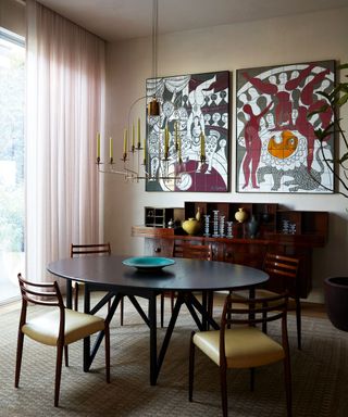 Modern dining room with dark wood table and chairs with large art on wall and modern pendant