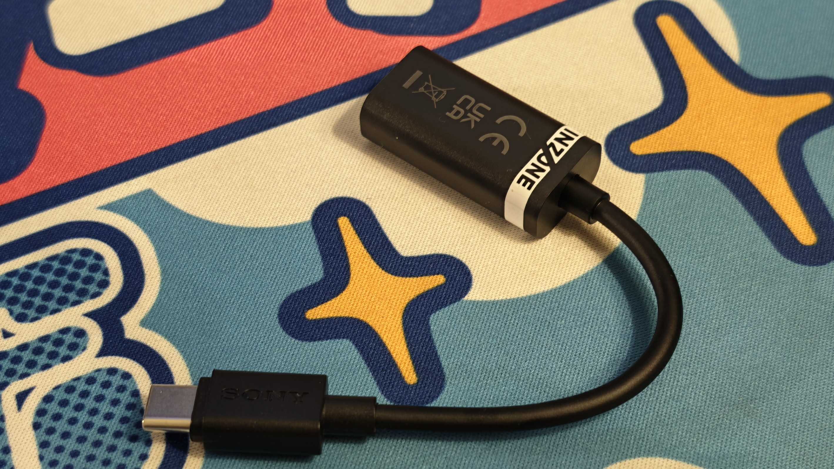 The Sony Inzone E9 gaming earbuds on a colorful desk mat.