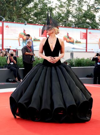 Lady Gaga wears a black lace headpiece by Philip Treacy at the Joker premiere.