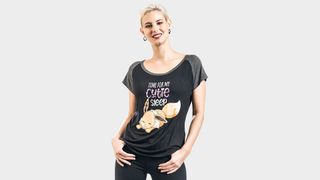A blonde woman wearing a black and grey t-shirt featuring a sleeping Eevee and cute slogan