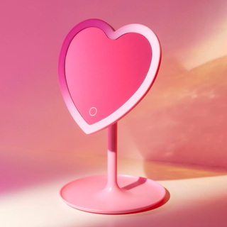 A pink heart shaped LED mirror on a pink sunset background