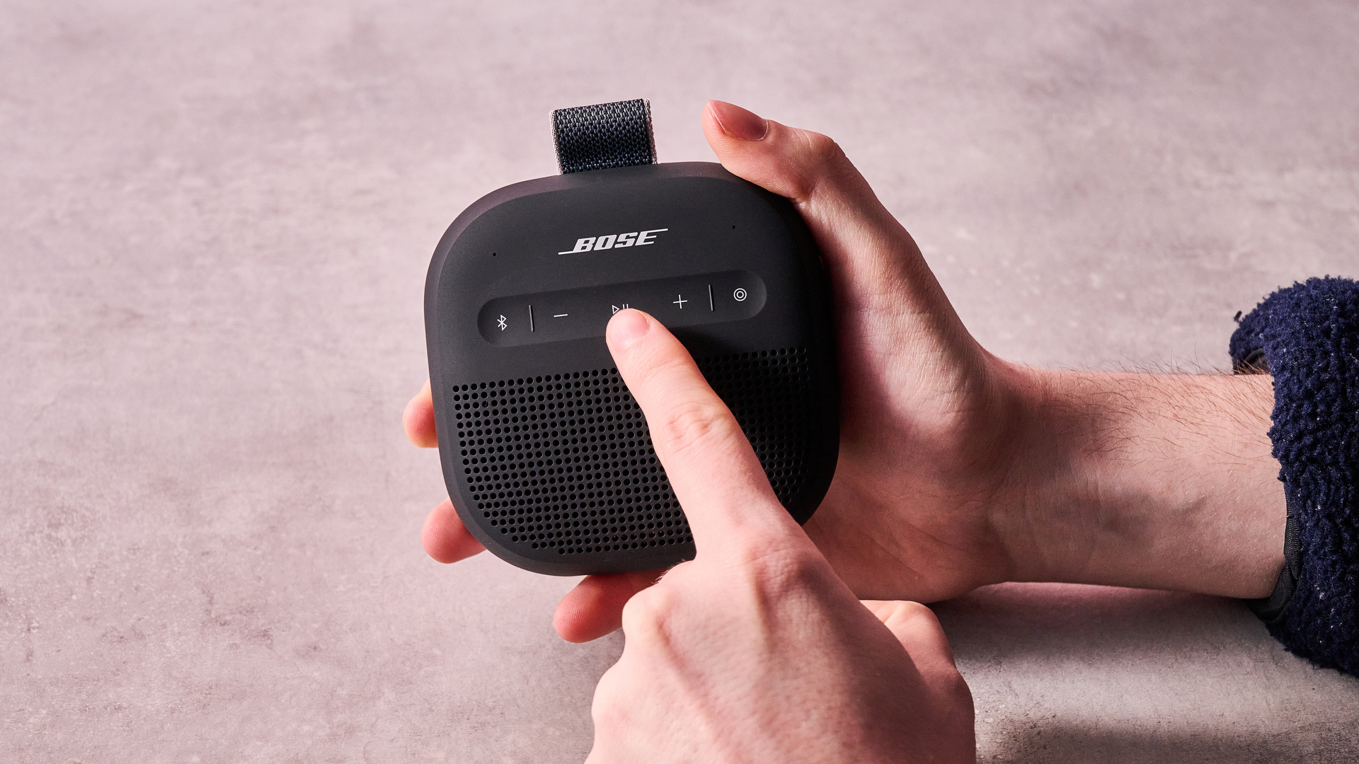 Man pressing play button on the Bose SoundLink Micro Gen 2