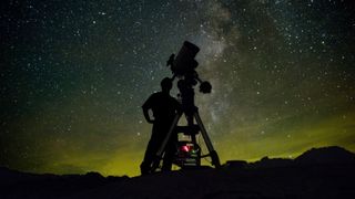 a person looks at the night sky through a telescope