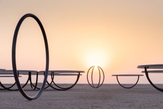 sunset, thin metal circular frames in desert, part of an artwork by Olafur Eliasson