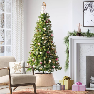 A decorated faux Christmas tree sits in a white-toned living room