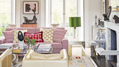  living room with pink sofa, cream leather armchairs, patterned cushions, patterned rug and marble fireplace