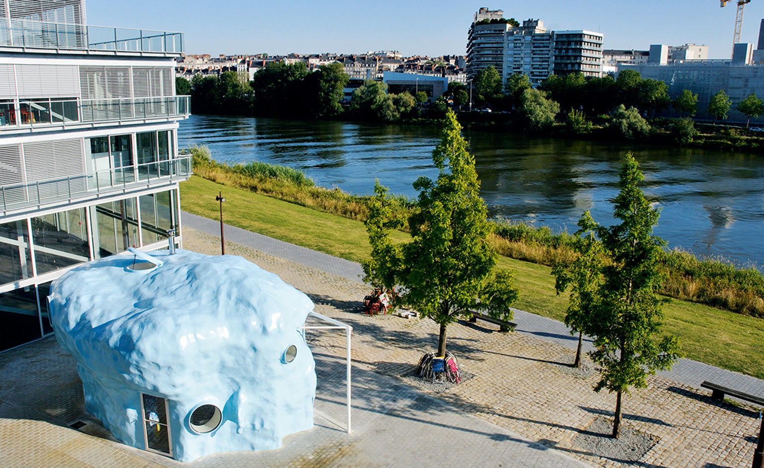 Amorphous blue sculpture-cum-bar next to trees and a river