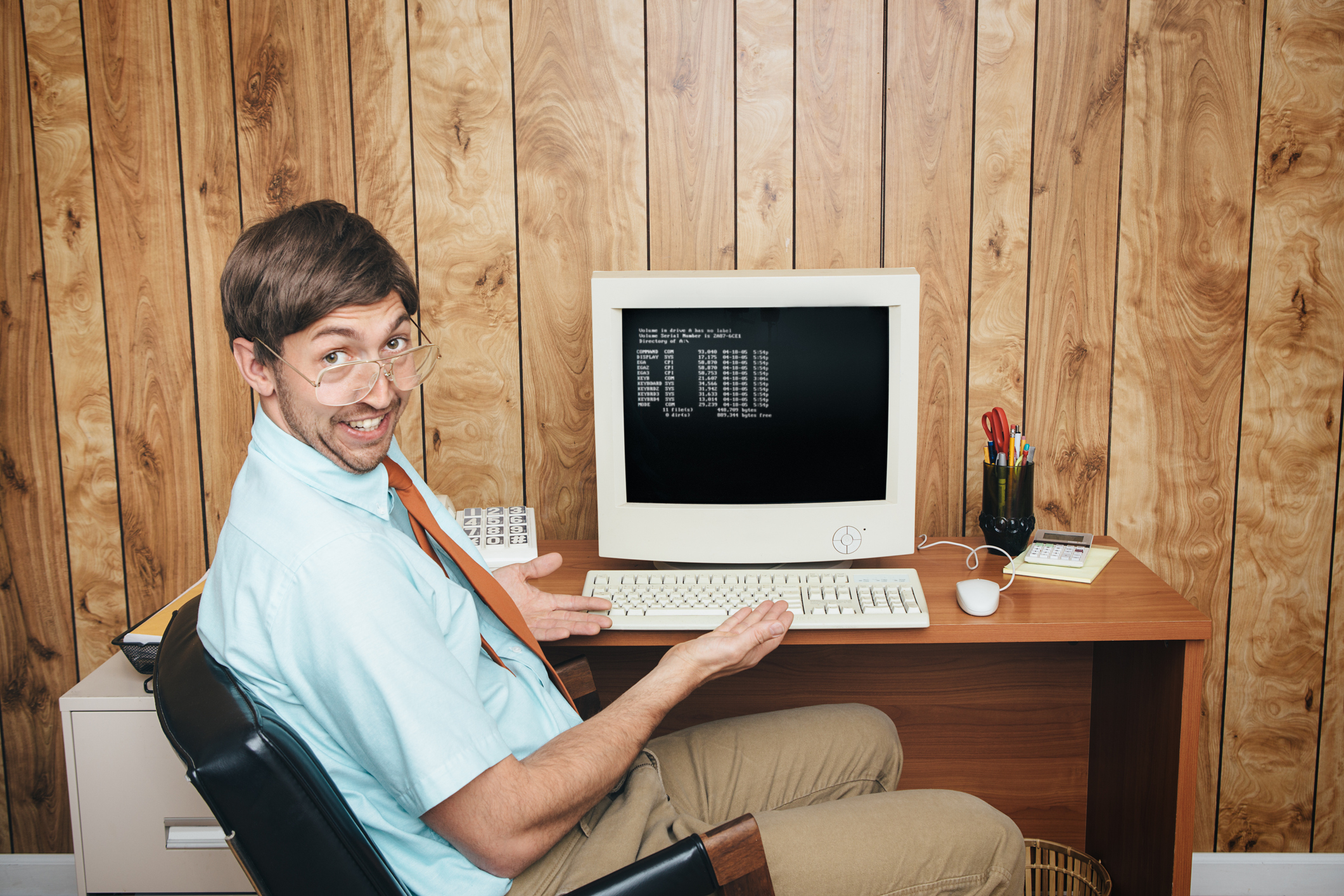Man sits at desk in '90s style office