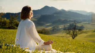 A woman meditates in the countryside