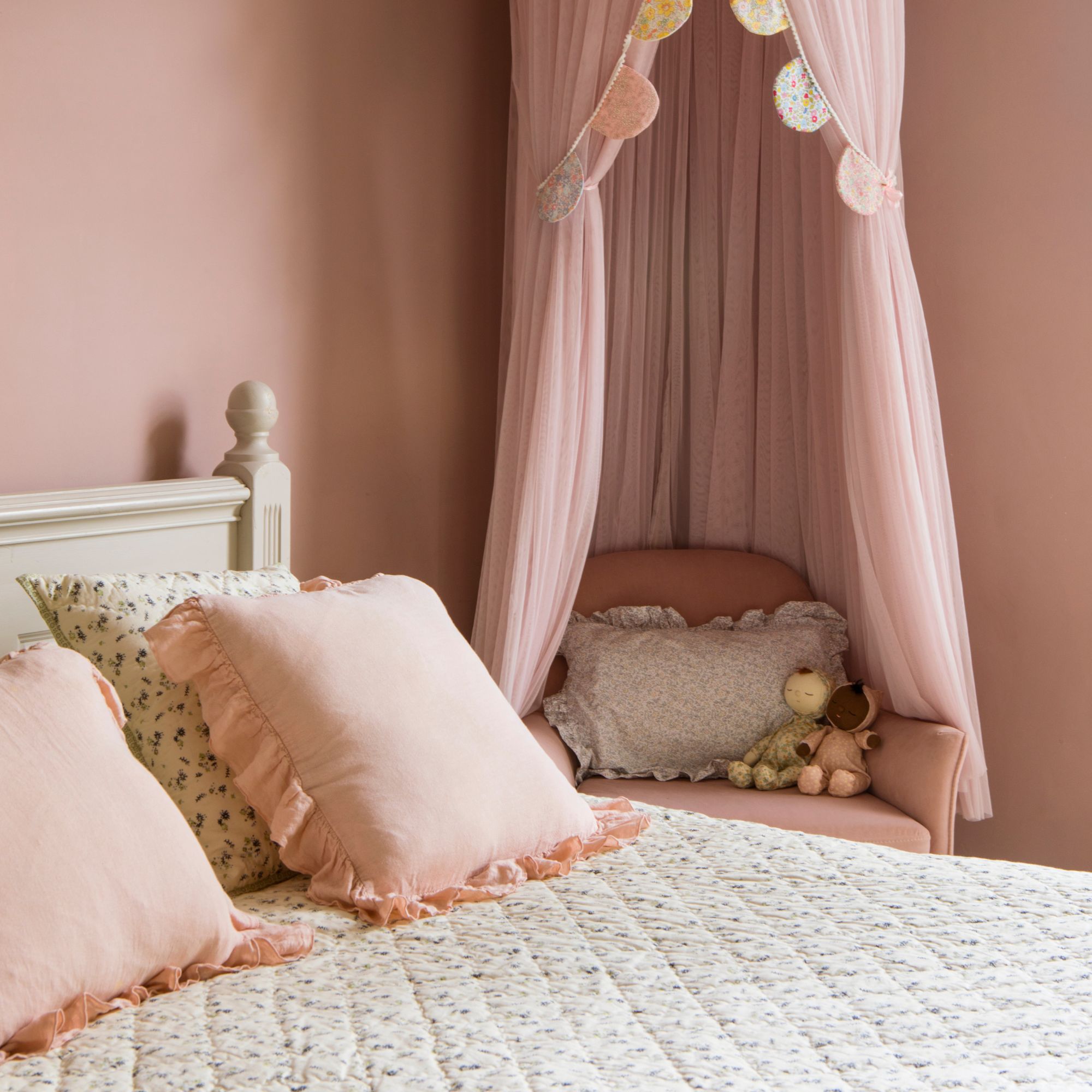 Pink bedroom with pink bedding and a pink teepee over a pink chair in the corner