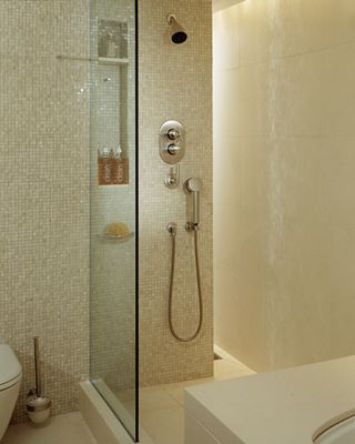 cream mosaic tiles in shower/bathroom with larger cream tiles on wall and floor, glass wall