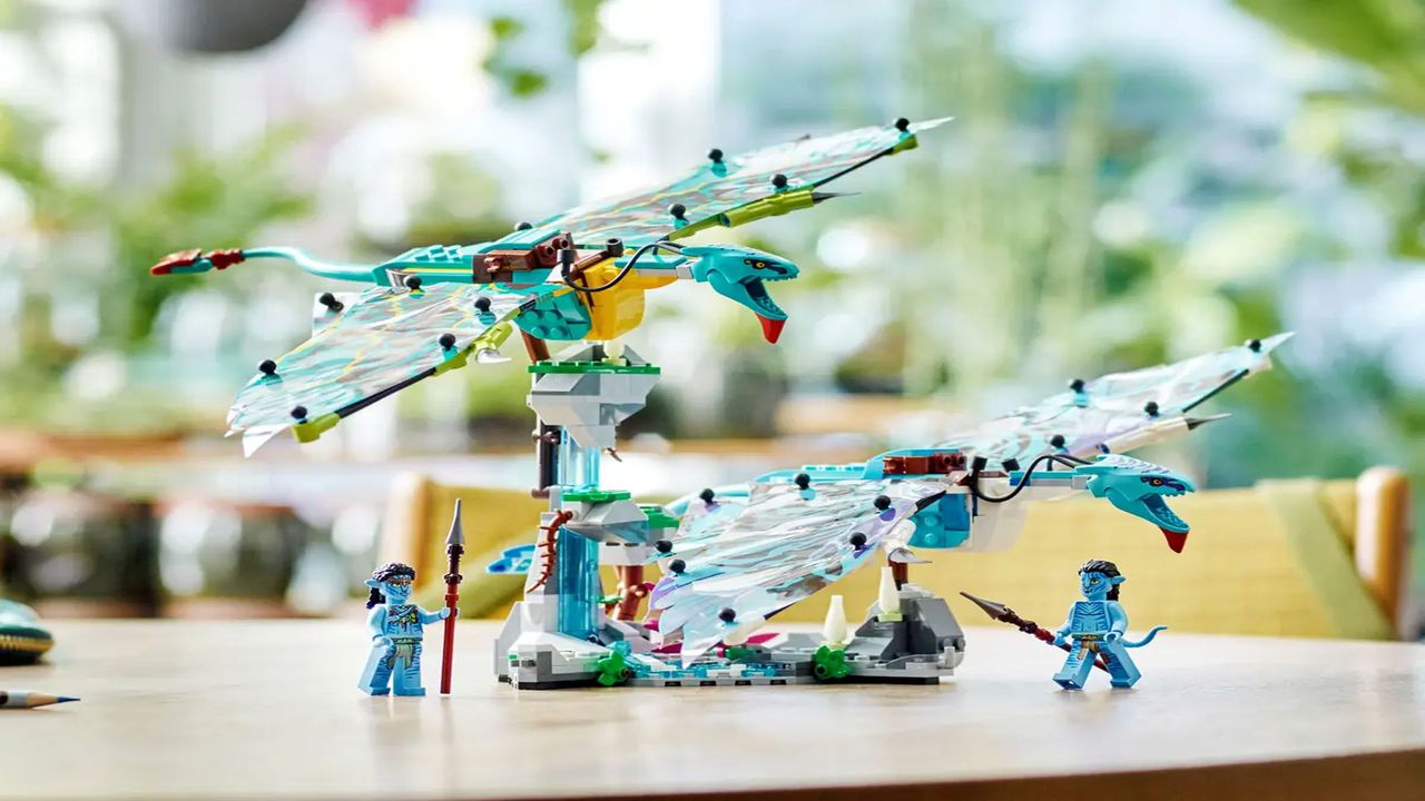 To brick-built winged animals are flying above some minifigures on a brown wooden table.