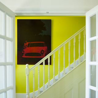 room with car wallpaper on yellow wall and white staircase