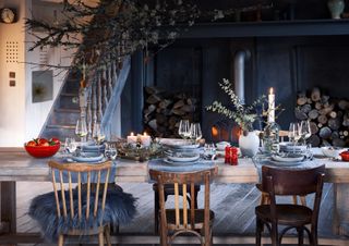 Blue festive room with big dining table, wooden chairs and red Christmas decs