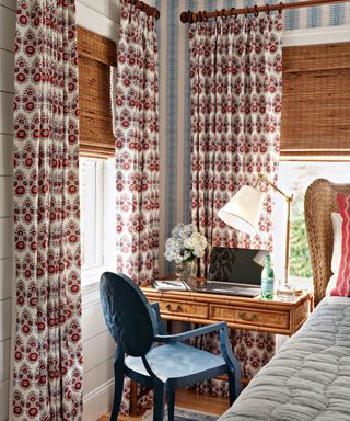 Bamboo desk in the corner of a bedroom with patterned curtains