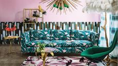 A maximalist living room painted bubble gum pink with different patterns all around the room. There is a tropical print sofa, a dragonfly rug, and tie-dye curtains.