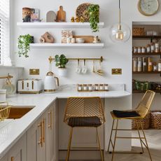 Kitchen with pale units, white work surface and gold metallic accessories