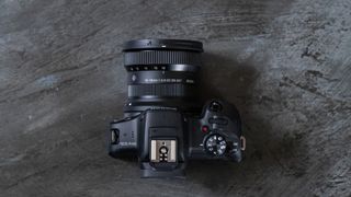 A Canon EOS R100 with Sigma 10-18mm f/2.8 DC DN | C lens attached on a metal background