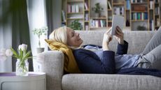 Woman lying on sofa looking at tablet