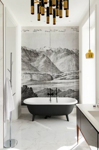 White bathroom with central charcoal landscape mural, black painted freestanding bath and gold accents