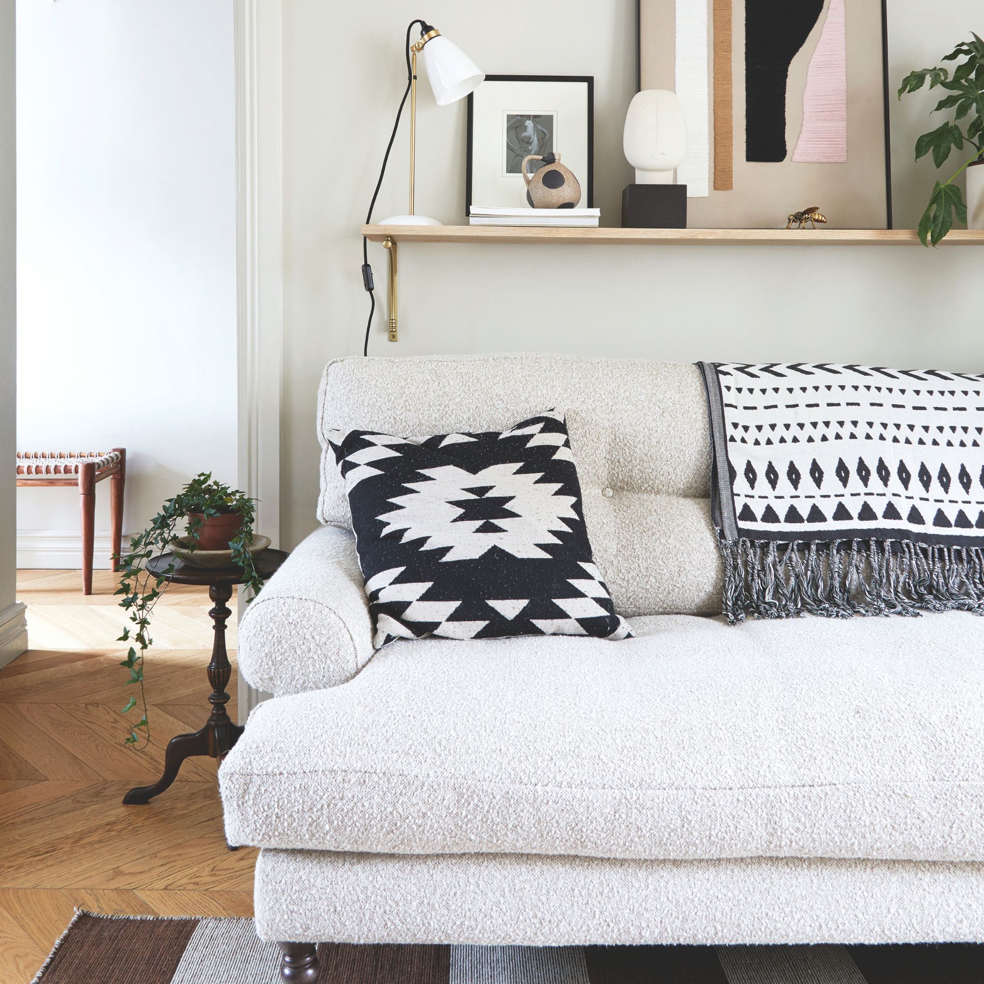 Beige painted living room with a boucle sofa and a shelf with decor above it