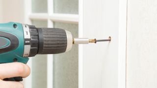 An electric drill drilling a screw in a wall