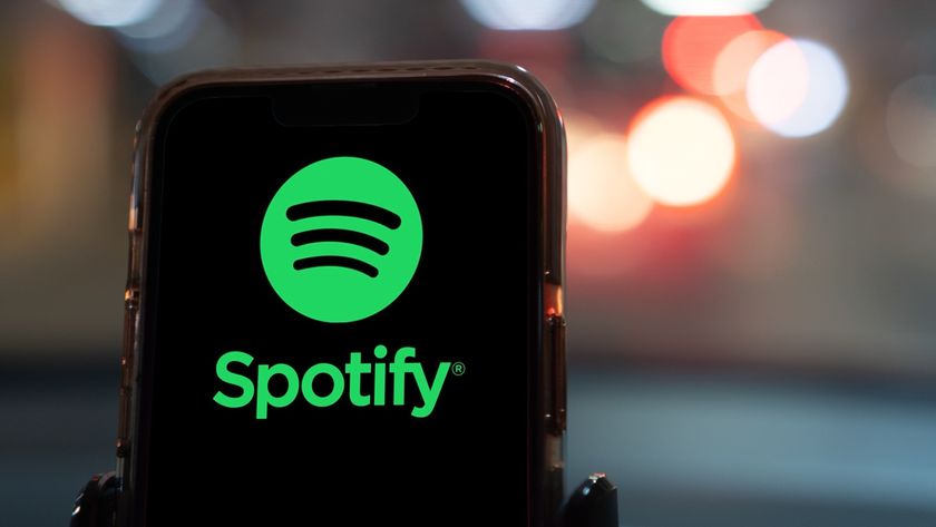 Spotify logo on phone, blurred city lights in background