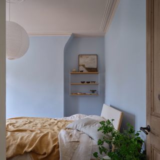 An airy bedroom with the walls painted in Farrow & Ball's Kakelugn blue shade and the ceiling in Scallop.