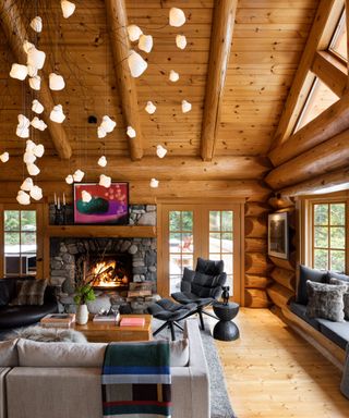 living room in log cabin with wooden walls and fire lit with statement light