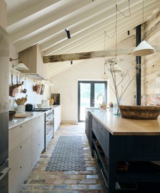 deVOL modern rustic kitchen with Sebastian Cox wood cabinets, ceiling beams and a brick floor