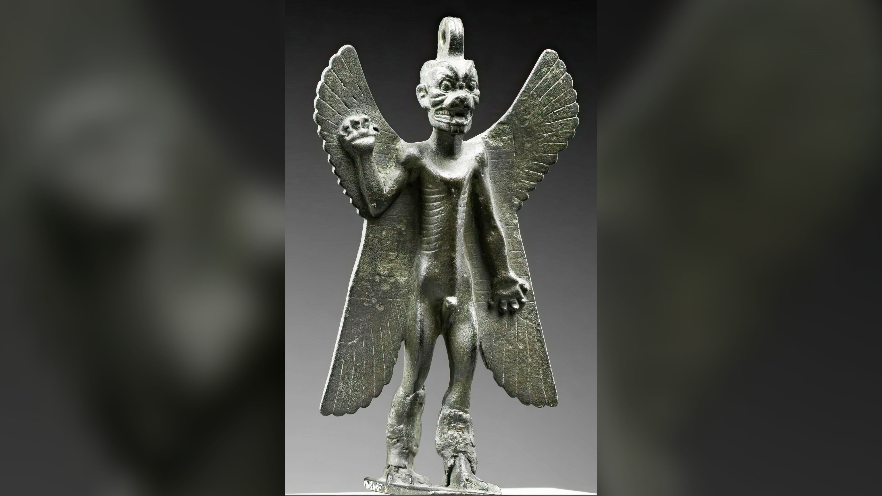 Bronze figurine of a demon-god with wings raising his right hand