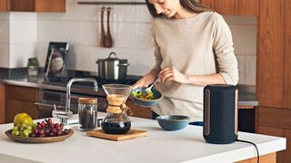 The Sony SRS-RA3000 on a kitchen counter as a woman makes a salad