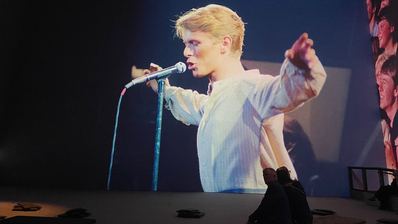 A projected image of David Bowie performing on stage for the exhibition David Bowie: You're Not Alone at Lightroom, London.