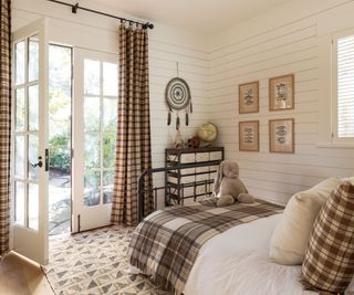bedroom with paneled walls brown check and plaid fabrics and french windows and wooden floors