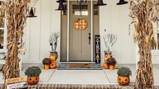 Halloween outdoor decor ideas with sage painted front door, gingham check pumpkin plaque pumpkin planters and floating witches hats