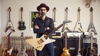Cesar Gueikian poses with a Gibson Explorer in front of a wall of Gibson guitars
