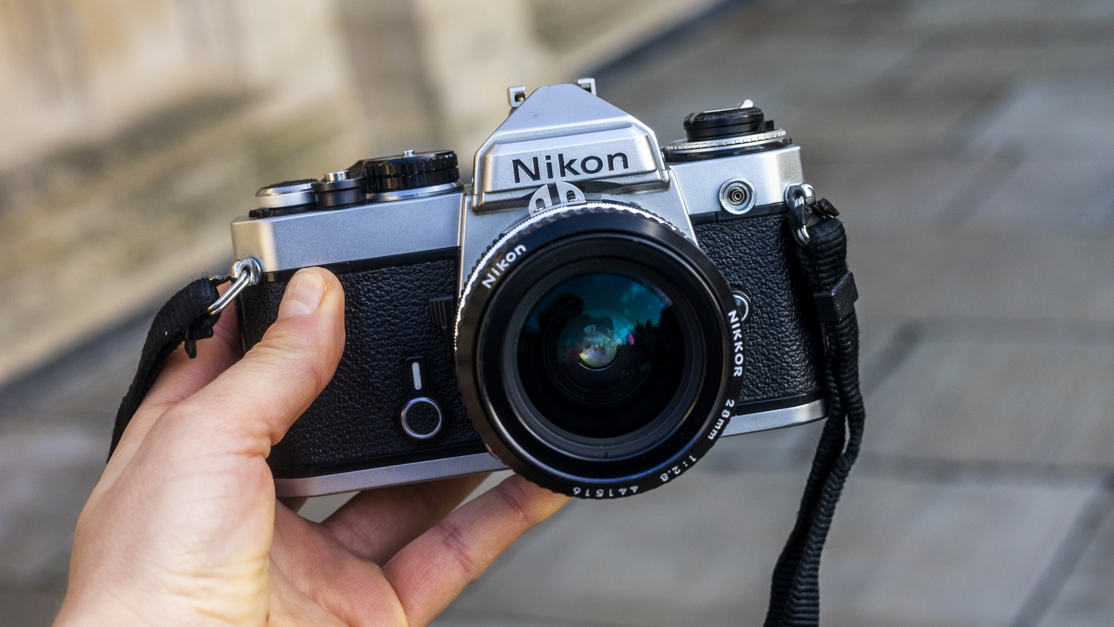 The Nikon Fe held by a photographer in front of a pavement
