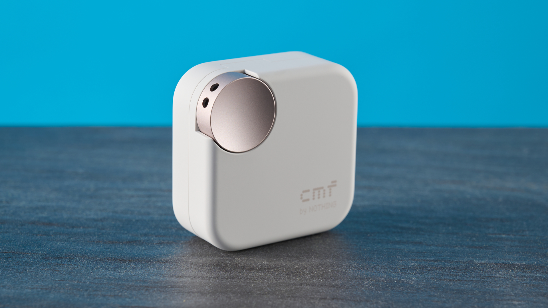 CMF Buds 2 Plus in light gray photographed in front of a blue background