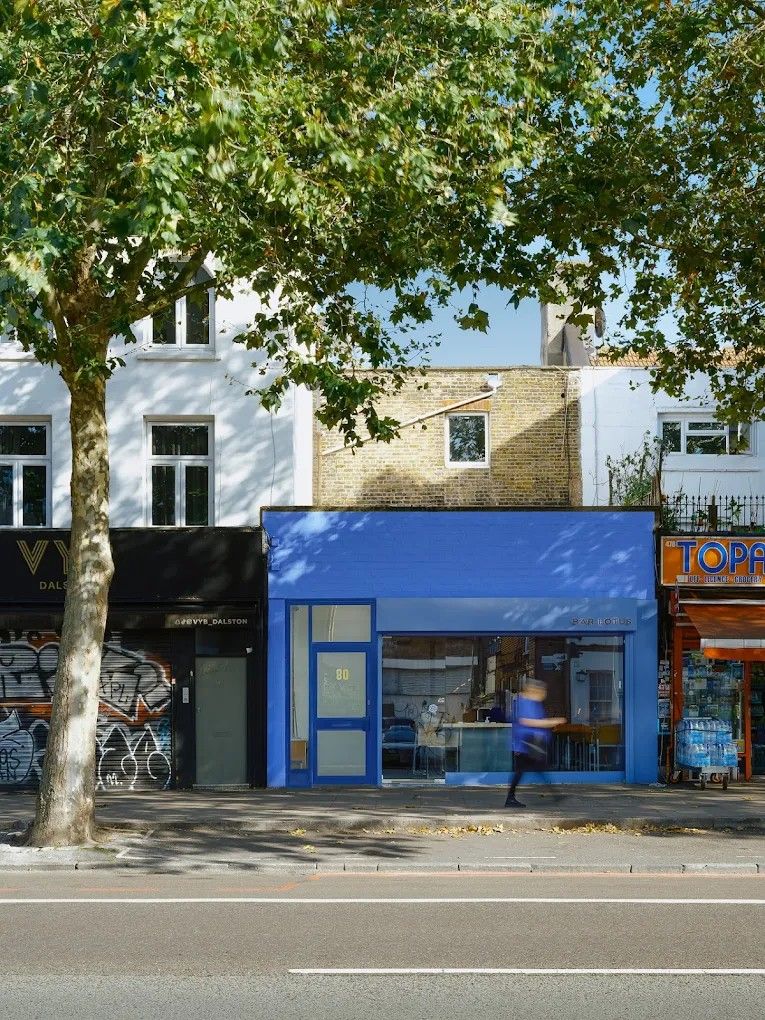 The exterior and interior of a blue and pink-tinted bar.
