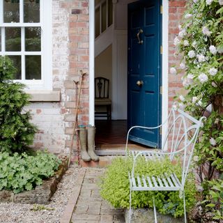 front garden with white metal bench and brick wall