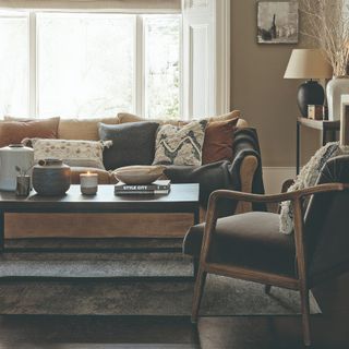 A beige-painted living room with a terracotta sofa and a black coffee table on a grey rug